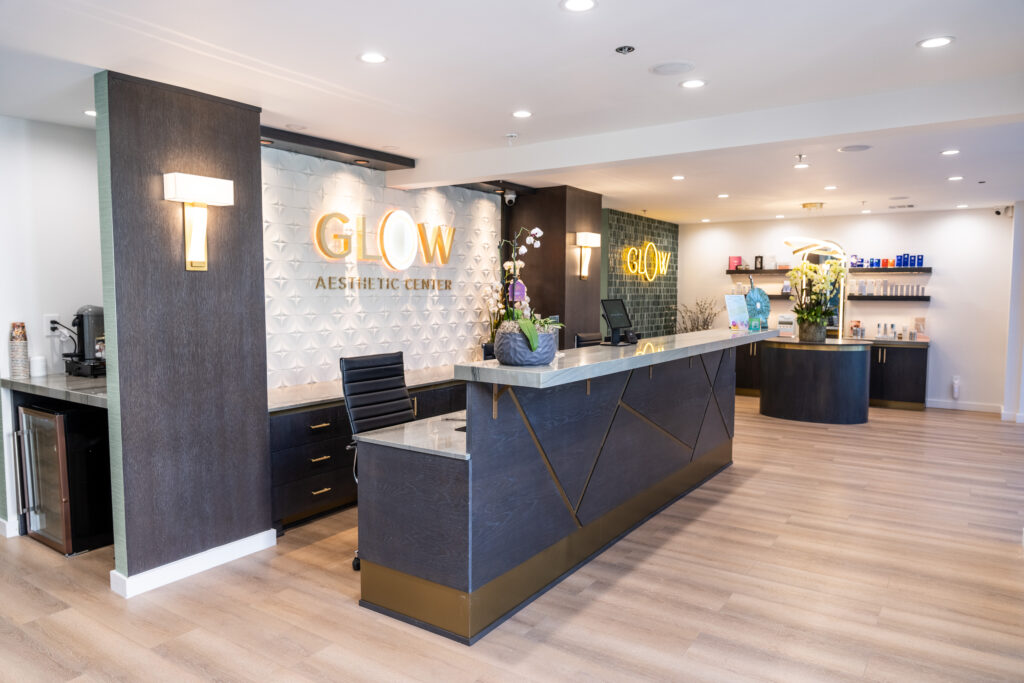 Modern reception area of Glow Aesthetic Center featuring elegant decor, a sleek front desk, and product displays. The space is well-lit with stylish lighting and a welcoming atmosphere, ideal for clients seeking aesthetic treatments.